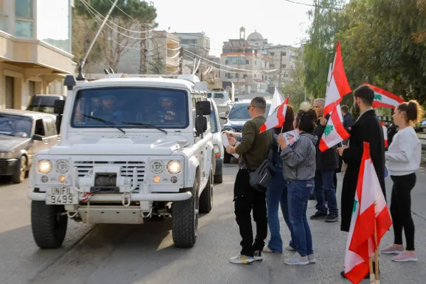 مواطنون يرفعون الأعلام اللبنانية ويقدمون السكاكر للسيارات العابرة ومنها التابعة للقوة المؤقتة للأمم المتحدة في لبنان «اليونيفيل» في بلدة القليعة بجنوب لبنان (أ.ف.ب)