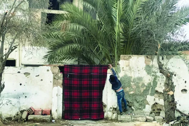 طفل يعلّق ستارة على باب داره المدمَّر في القصير (أرشيفية - الشرق الأوسط)
