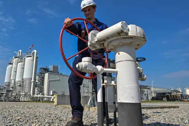 عامل يحرك صماماً في أنابيب غاز بمنشأة أوروبية (أ.ف.ب)