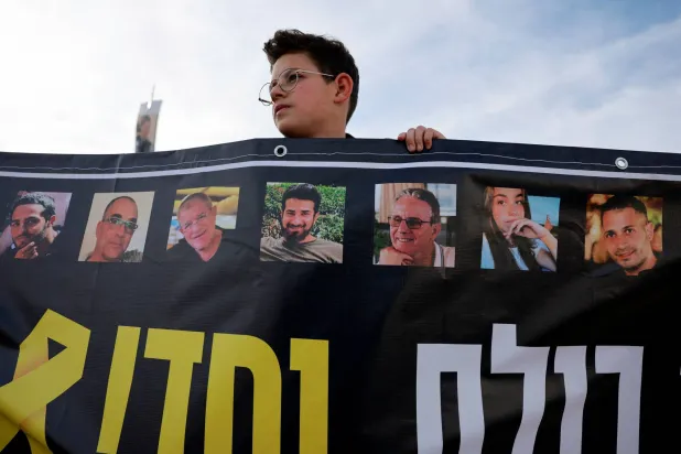 متظاهر يحمل لافتة خلال تجمع عائلات الرهائن الإسرائيليين للمطالبة بصفقة تعيد جميع المحتجزين في غزة خارج اجتماع بين ممثلي الرهائن ورئيس الوزراء الإسرائيلي بنيامين نتنياهو بالقدس (رويترز)