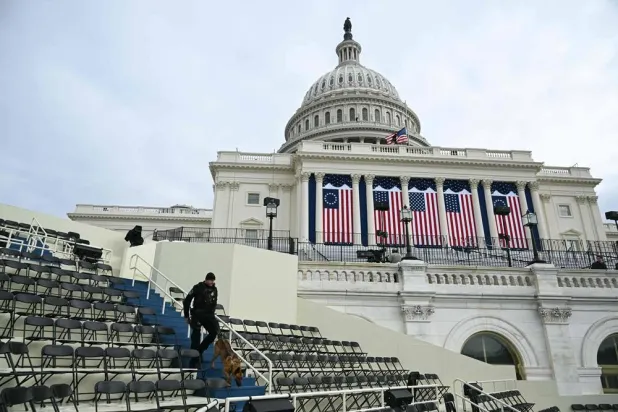 A US Capitol Police officer walks with a K-9 dog in the seating area of the platform stage on the West Front of the US Capitol building, where the presidential inauguration traditionally takes place, on January 17, 2025, in Washington, DC. (AFP)