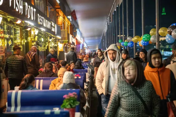 أتراك يتجولون بين المقاهي على كوبري عالاطا في إسطنبول مطلع العام الجديد (د.ب.أ)