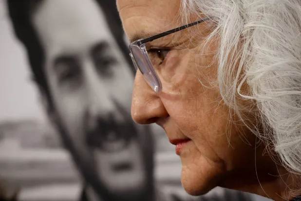 ديبرا تايس أمام صورة لابنها الصحافي أوستن تايس الذي اختطف أثناء تغطيته الأحداث في سوريا عام 2012 (رويترز)