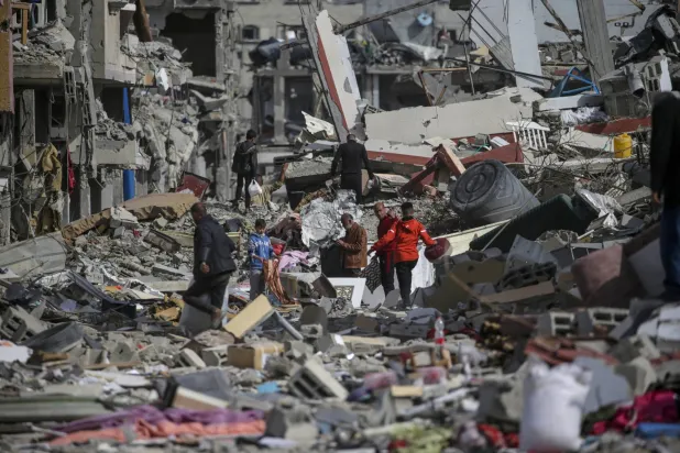 فلسطينيون يتفقدون منازلهم المدمرة في رفح بعد عودتهم إليها (إ.ب.أ)