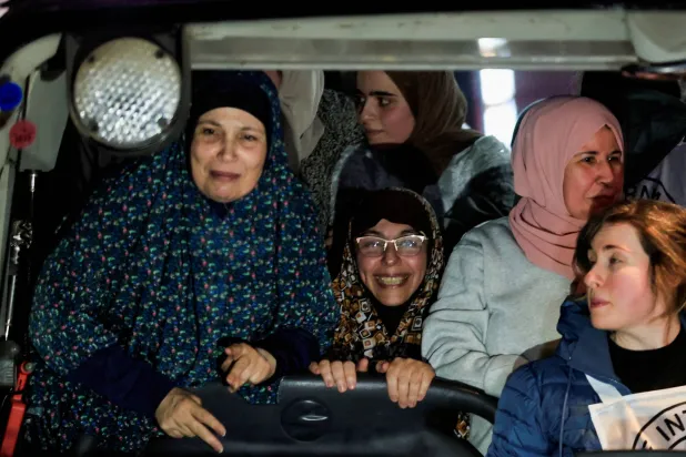 أسيرات فلسطينيات داخل حافلة يوم الأحد بعد إطلاق سراحهن من سجن إسرائيلي (رويترز)