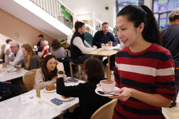 موظفة تحمل فنجاناً من القهوة في أحد المقاهي بلندن (رويترز)