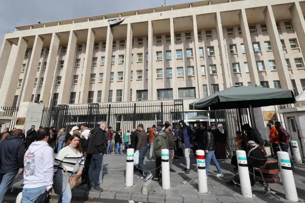مواطنون يصطفون أمام المقر الرئيس لمصرف سوريا المركزي في دمشق (أ.ف.ب) 