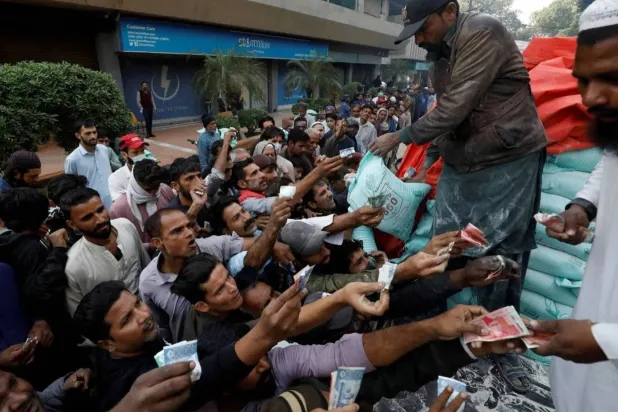 رجال يحاولون شراء أكياس الدقيق المدعوم من شاحنة في كراتشي بباكستان (رويترز)