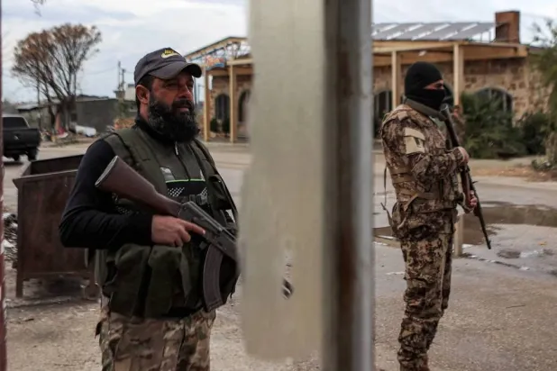 Fighters from Syria's new leadership stand at a checkpoint near the entrance of the Hmeimim military base in Latakia province, December 29, 2024. (AFP) 