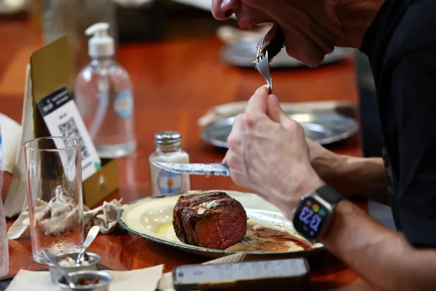 رجل يأكل لحماً مشوياً بمطعم في بوينس آيرس (رويترز)