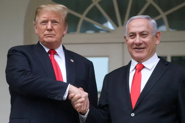 الرئيس الأميركي دونالد ترمب يصافح رئيس الوزراء الإسرائيلي بنيامين نتنياهو في أثناء التقاط صورة لهما في الرواق الغربي بالبيت الأبيض في واشنطن 25 مارس 2019 (رويترز)