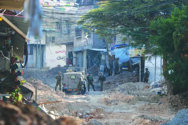 Batı Şeria'daki Tulkerim Mülteci Kampı'na düzenlenen bir baskın sırasında araçlarının yanında duran İsrail askerleri (AFP)
