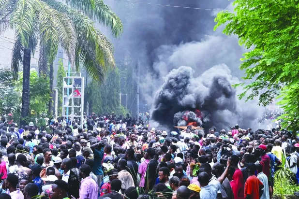 
متظاهرون يضرمون النار في حواجز مؤقتة خلال مسيرة في كينشاسا أمس (إ.ب.أ)