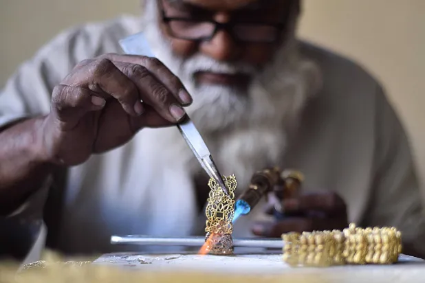 صانع ذهب يصنع المجوهرات في ورشة عمل في كراتشي بباكستان (إ.ب.أ)