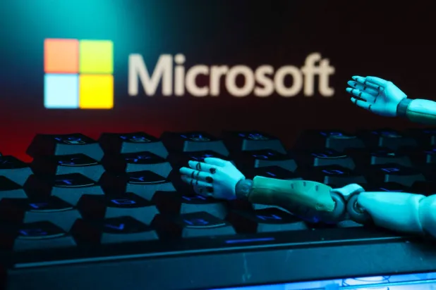 يظهر شعار «مايكروسوفت» ولوحة المفاتيح والأيدي الآلية في هذا الرسم التوضيحي (رويترز)