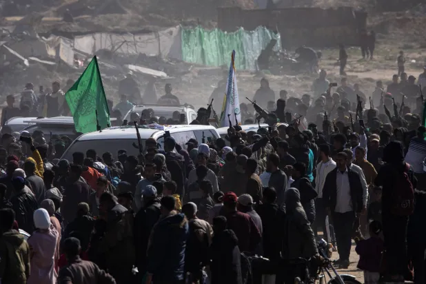 مدنيون ومسلحون فلسطينيون يتجمعون في موقع إطلاق سراح الرهائن الإسرائيليين بخان يونس (إ.ب.أ)