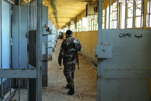 أحد عناصر الأمن السوري يمشي أمس بين أطلال زنازين سجن صيدنايا العسكري على مشارف دمشق (أ.ب)