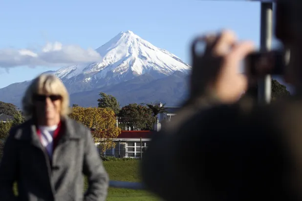 رجل يلتقط صورة لزوجته أمام جبل تاراناكي في نيوزيلندا (أ.ب)