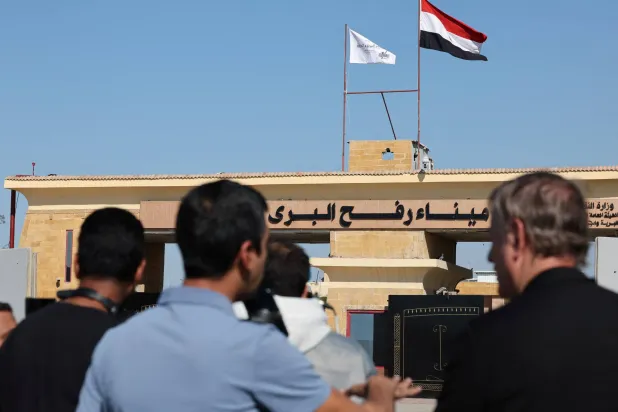 مواطنون يقفون بالقرب من معبر رفح الحدودي بين مصر وقطاع غزة مع إعادة فتحه (رويترز)