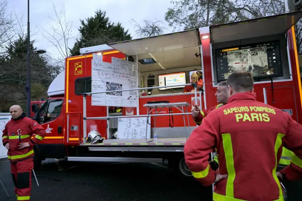 رجال الإطفاء يتلقون التعليمات أثناء تجمعهم بمركز القيادة بجوار مبنى بلدية الدائرة الثانية عشرة في باريس (أ.ف.ب)