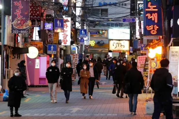 مارَّة يتسوقون في أحد الشوارع التجارية بالعاصمة الكورية سيول (رويترز)