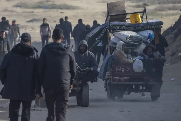 فلسطينيون يشقون طريقهم بين أنقاض المباني المدمرة وسط وقف إطلاق النار بين إسرائيل و«حماس» على طريق الرشيد بمدينة غزة (إ.ب.أ)