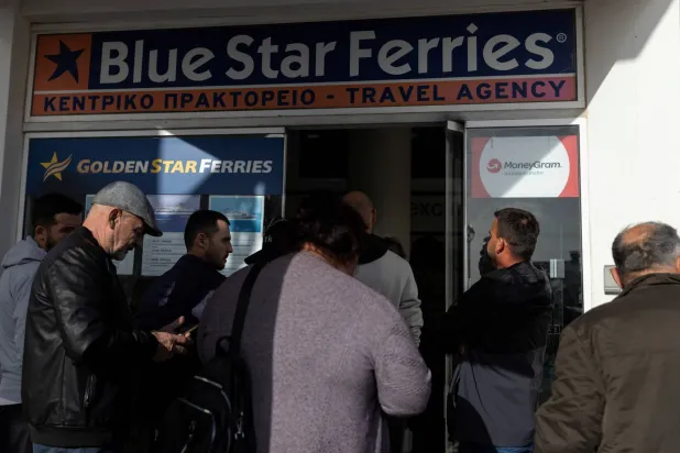 أشخاص في انتظار شراء تذاكر العبّارة لمغادرة سانتوريني (رويترز)