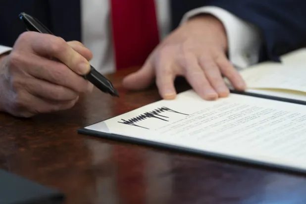 الرئيس الأميركي دونالد ترمب يوقّع على قرار تنفيذي في المكتب البيضاوي بالبيت الأبيض (إ.ب.أ)