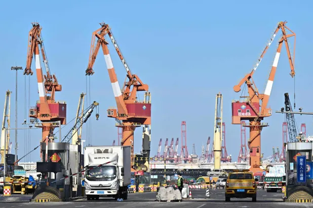 شاحنات تنقل حاويات معدّة للتصدير في ميناء ليانغانغ داغو شمال غربي الصين (أ.ف.ب)