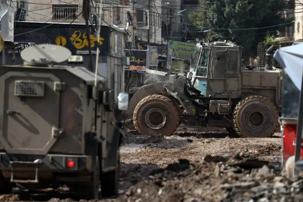 آليات إسرائيلية في طريق دمرته بالقرب من المدخل الرئيسي لمخيم جنين للاجئين الأربعاء (إ.ب.أ)