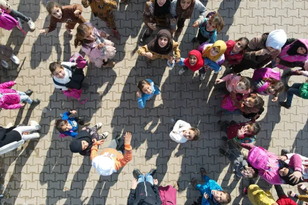 تلامذة سوريون يلعبون خلال الاستراحة في باحة مدرستهم في مخيم للاجئين في أعزاز قرب الحدود التركية (غيتي)