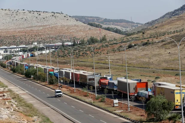 شاحنات تركية تحمل أكياساً من الإسمنت تنتظر العبور إلى سوريا بالقرب من بوابة جيلفاجوزو الحدودية التي تقع مقابل معبر باب الهوى السوري بمحافظة هاتاي بتركيا في الأول من نوفمبر 2012 (رويترز)