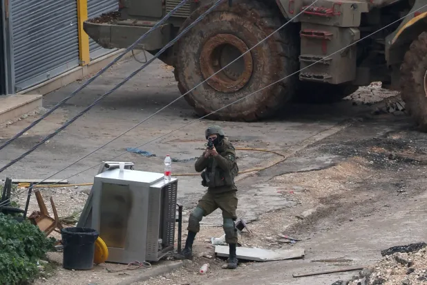 جندي إسرائيلي يصوب سلاحه في مخيم الفارعة بالضفة الغربية (إ.ب.أ)