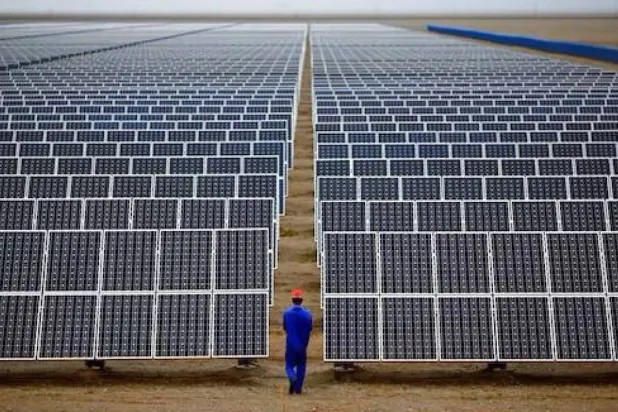 عامل صيني يسير وسط حقل للطاقة الشمسية في مقاطعة غانسو الصينية (رويترز)