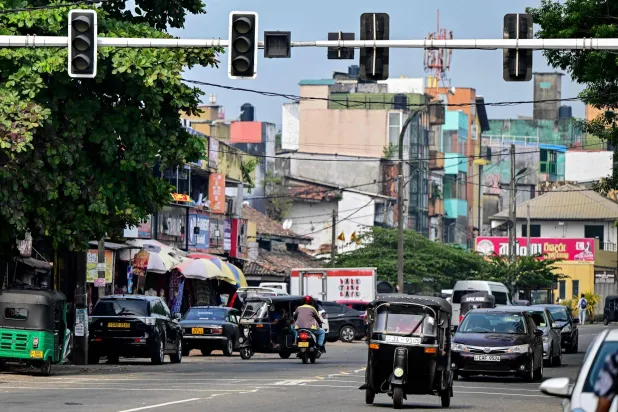 ركاب يمرون بإشارة مرور معطلة بعد انقطاع التيار الكهربائي على مستوى البلاد في جالي في 9 فبراير 2025 (أ.ف.ب)