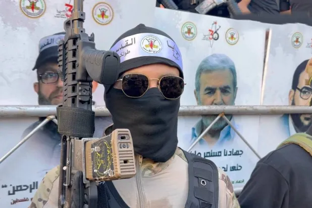 أحد عناصر «سرايا القدس-كتيبة طولكرم» وخلفه صوره زياد النخالة الأمين العام لحركة «الجهاد الإسلامي» في فلسطين (كتيبة طولكرم)