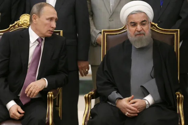 الرئيس الروسي بوتين يتحدث مع الرئيس الإيراني السابق حسن روحاني خلال محادثاتهما بعد انتهاء القمة الثالثة لمنتدى الدول المصدرة للغاز في طهران 23 نوفمبر 2015 (أرشيفية - غيتي)