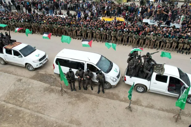 صورة ملتقطة في 8 فبراير 2025 في دير البلح بقطاع غزة خلال تسليم كتائب القسام لرهائن إسرائيليين للصليب الأحمر ضمن صفقة التبادل (رويترز)