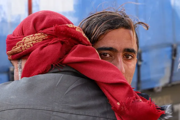 شاب صغير يعانق مسناً بعد حصوله على موافقة لمغادرة مخيم الهول في الحسكة شمال شرقي سوريا الأحد الماضي (أ.ف.ب)