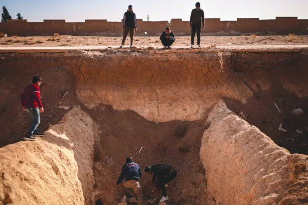 أشخاص يبحثون عن جثث في خندق يُعتقد أنه استُخدم مقبرةً جماعية على مشارف دمشق ديسمبر الماضي (أ.ف.ب)