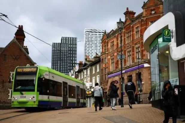 يمشي الناس على شارع رئيسي في كرويدون جنوب لندن (رويترز)