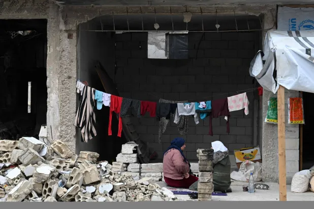 نساء يجلسن أمام مبنى متضرر من الحرب في بلدة القصير في محافظة حمص وسط سوريا (أ.ف.ب)