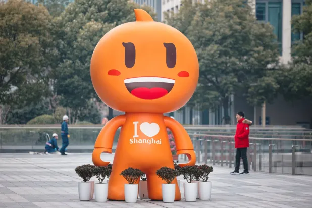 مشاة يمرون أمام تميمة «علي بابا» أمام مقر الشركة في مدينة شنغهاي الصينية (إ.ب.أ)