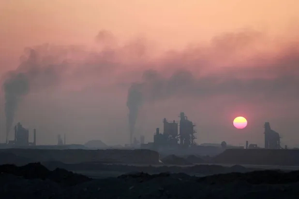 الشمس تغرب وسط دخان مصفاة نفط على مشارف الحلة وسط العراق (أ.ف.ب)