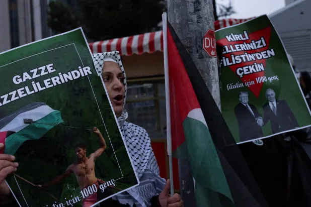متظاهرون من حركة «ألف شاب من أجل فلسطين» التركية في إسطنبول يرفعون لافتات «ارفعوا أيديكم القذرة عن غزة» و«غزة للغزيين» (رويترز)