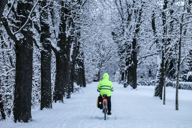 رجل يقود دراجته وسط الثلوج في برلين (إ.ب.أ)