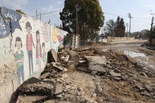 طريق متضرر أثناء عملية عسكرية إسرائيلية مستمرة في مدينة جنين بالضفة الغربية الأحد (إ.ب.أ)