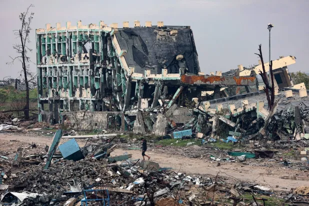 شاب يسير أمام مدرسة لحقت بها أضرار جسيمة في بيت حانون شمال قطاع غزة (أ.ف.ب)