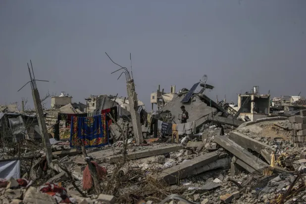 شاب فلسطيني يقف خارج مأوى عائلته الذي أقيم بين أنقاض المباني المدمرة في مخيم جباليا شمال قطاع غزة (إ.ب.أ)