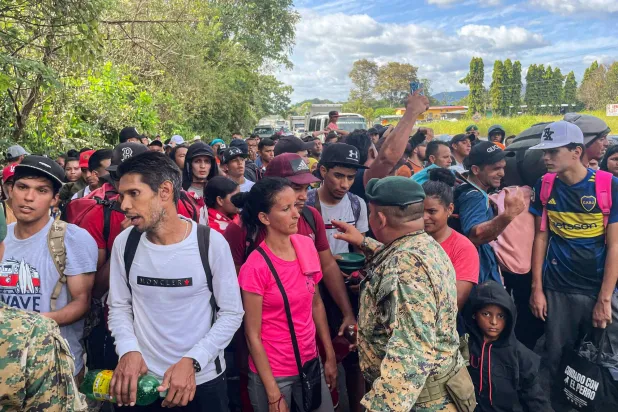 مهاجرون يحاولون إقناع حرس الحدود البنمي بعبور الحدود قادمين من كوستاريكا في رحلة العودة إلى فنزويلا (أ.ف.ب)